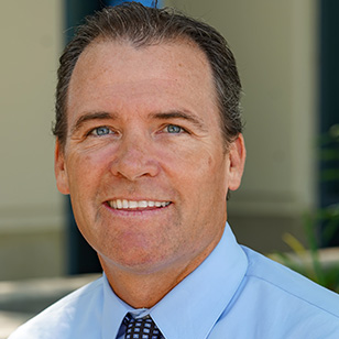 Headshot of Dr. Tyler Smith wearing a light blue dress shirt and tie