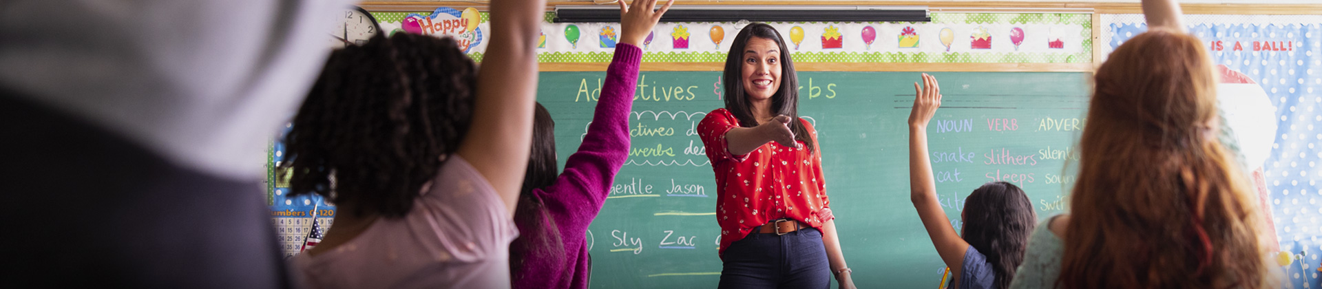 Abigail J. in a classroom with students. She smiles as she calls on a student for the answer.