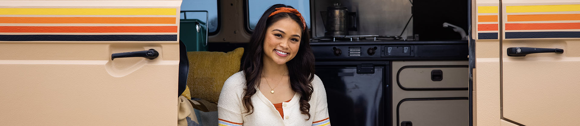 Krystal F. - Class of 2021, stands in front of an open retro camper van