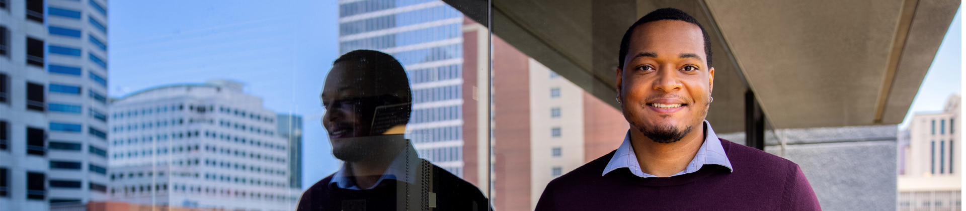 Kerry J. standing next to a window on the military admissions building 