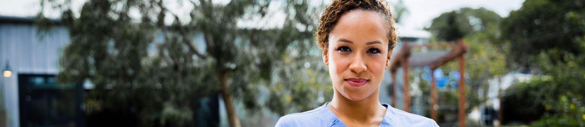 woman in scrubs stands outside in a National campus