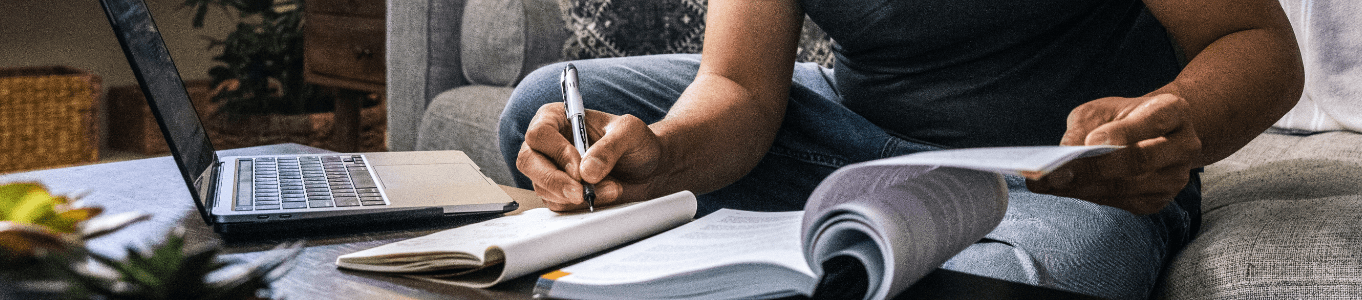 Can Music Help You Study and Focus? A man sitting on couch taking notes as he flips through textbook