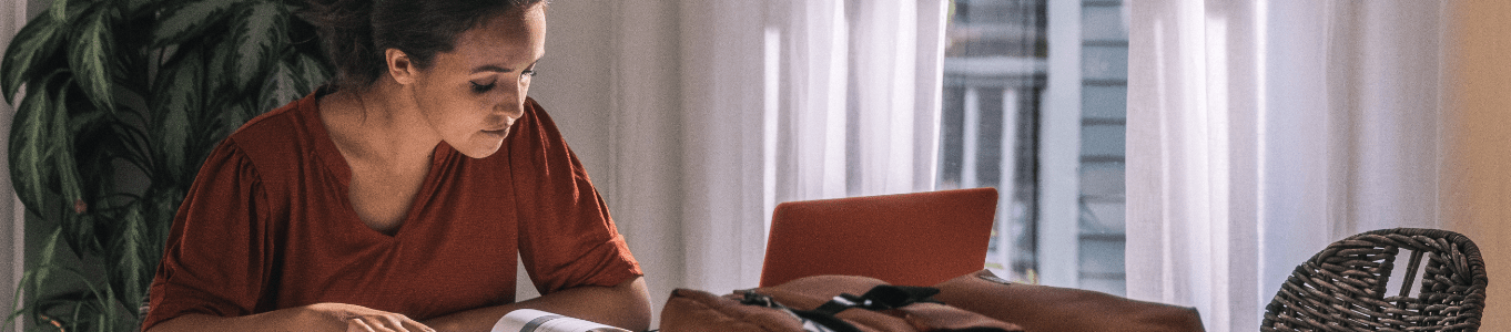 woman looking down at textbook studying in her home