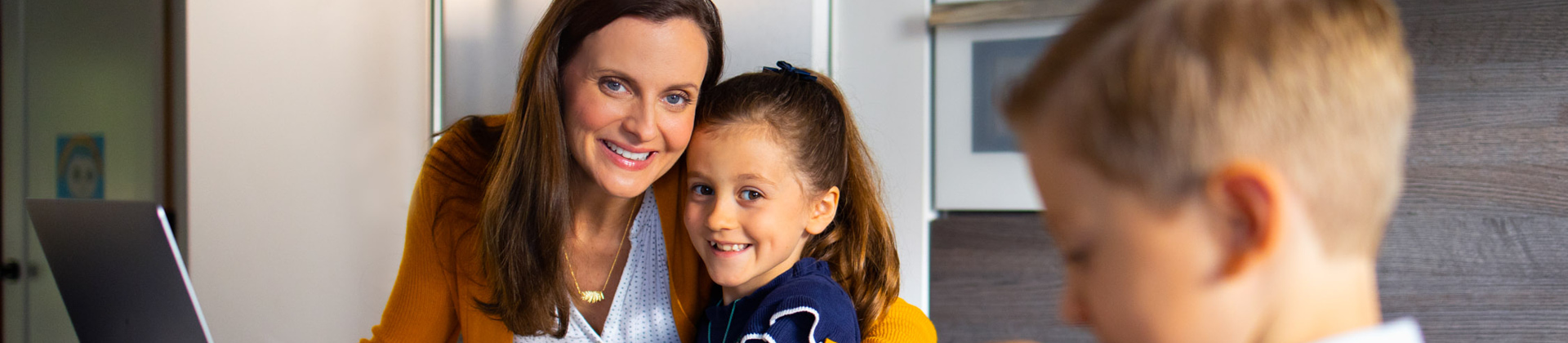 woman with preschooler on lap looking towards preschool aged boy