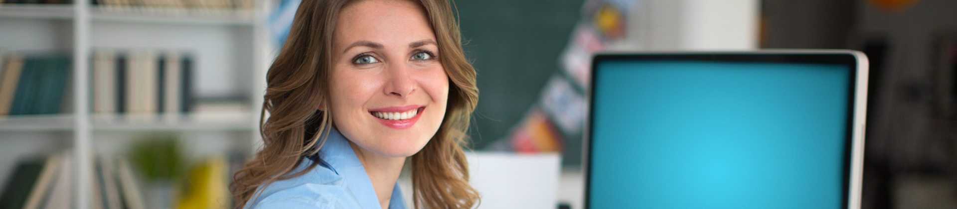 Women smiling at camera with laptop to her right. 